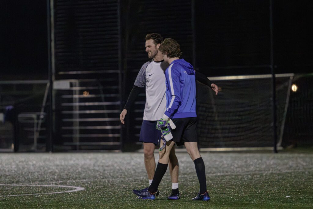 Twee jongens op het veld na de wedstrijd met armen over elkaar heen